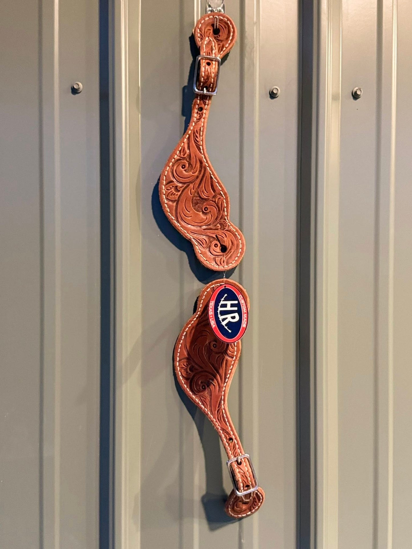 Close-up of detailed hand-tooled Western pattern on Big Sky spur straps
