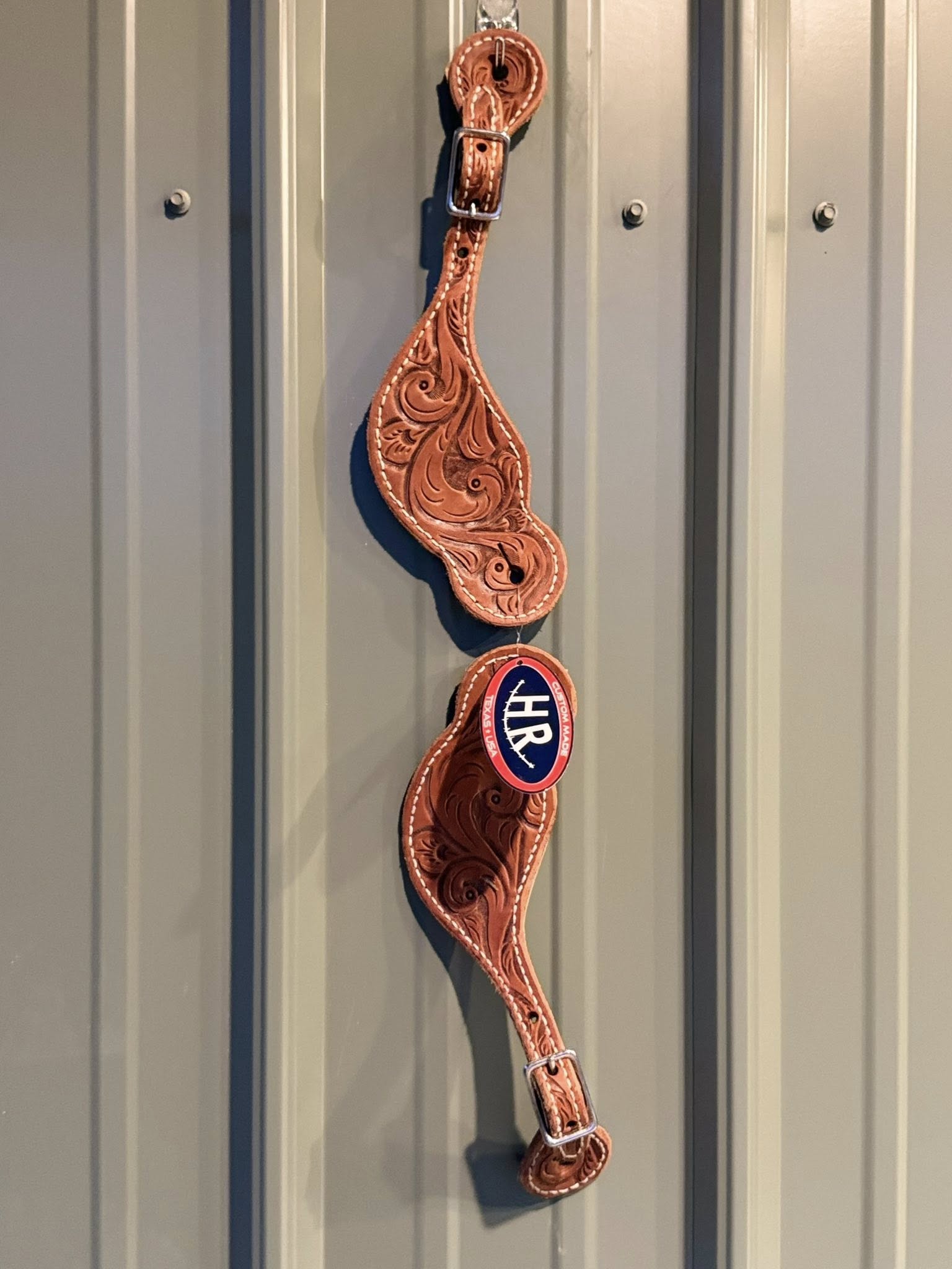 Close-up of detailed hand-tooled Western pattern on Big Sky spur straps
